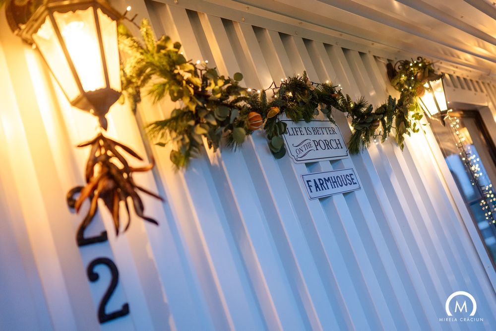 A decorated wedding reception venue with white draping, hanging lights and greenery creating an elegant ambiance.
