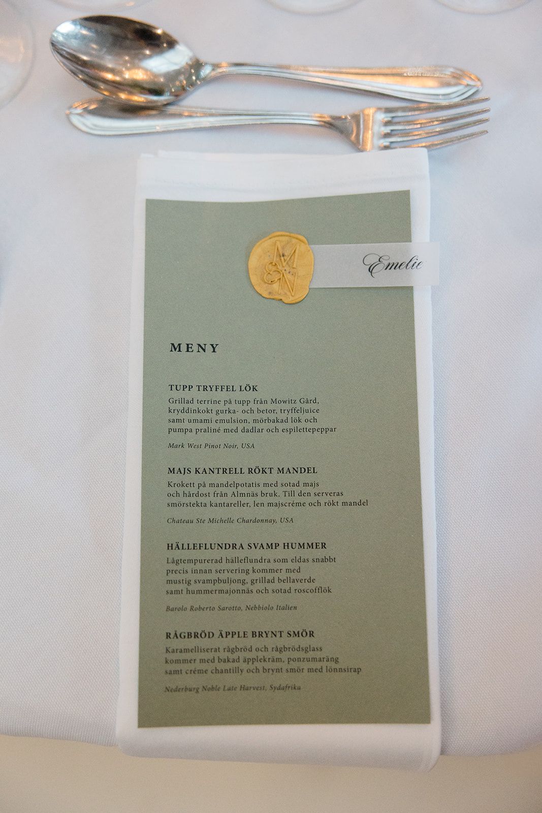 Wedding guests laugh and enjoy conversation during an elegant reception dinner in a bright windowed venue.