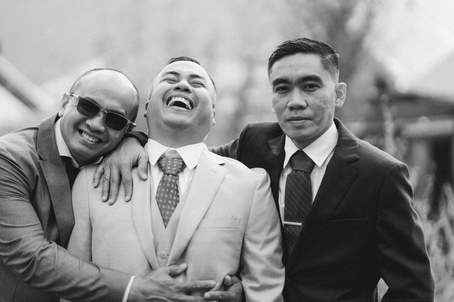 Wedding party members in formal attire share laughs during outdoor photos.