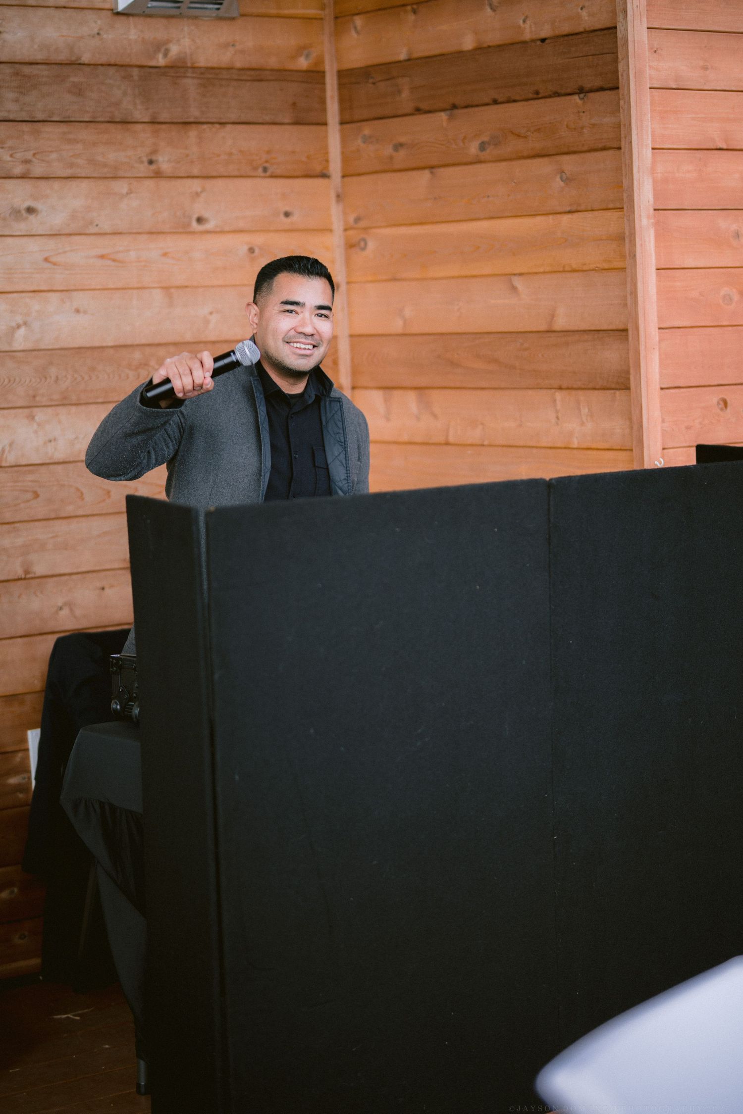 DJ booth setup with black facade in a rustic wooden venue.