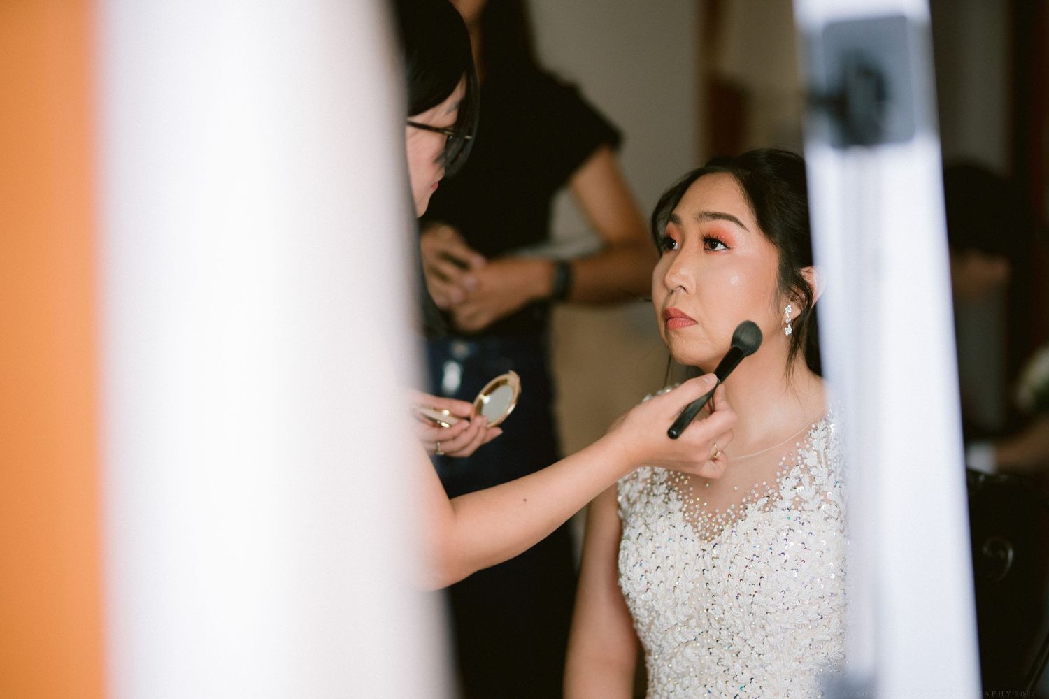 Close-up shot of bride getting makeup applied during wedding preparations.