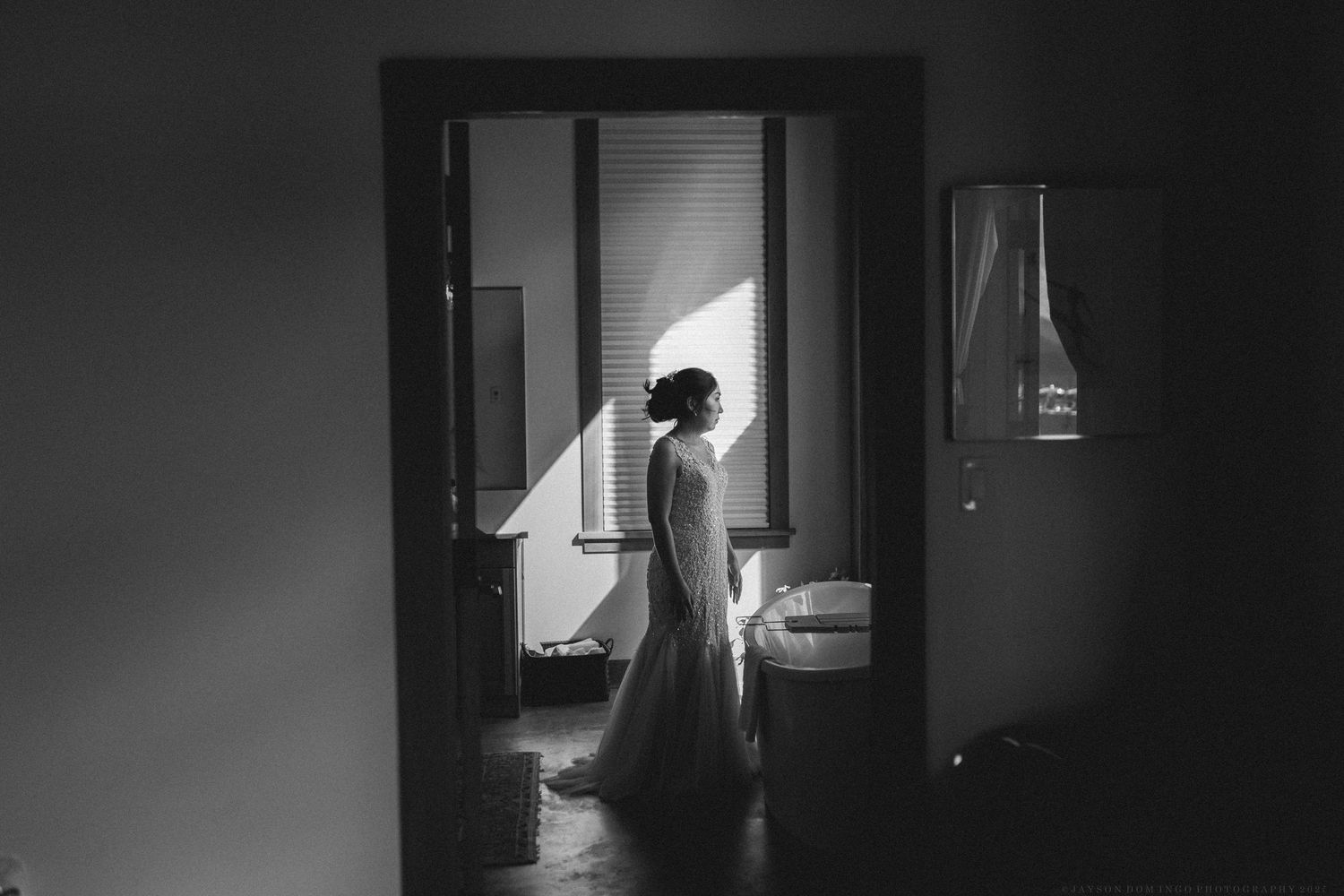Silhouette of someone in a wedding dress framed in a doorway with dramatic lighting.