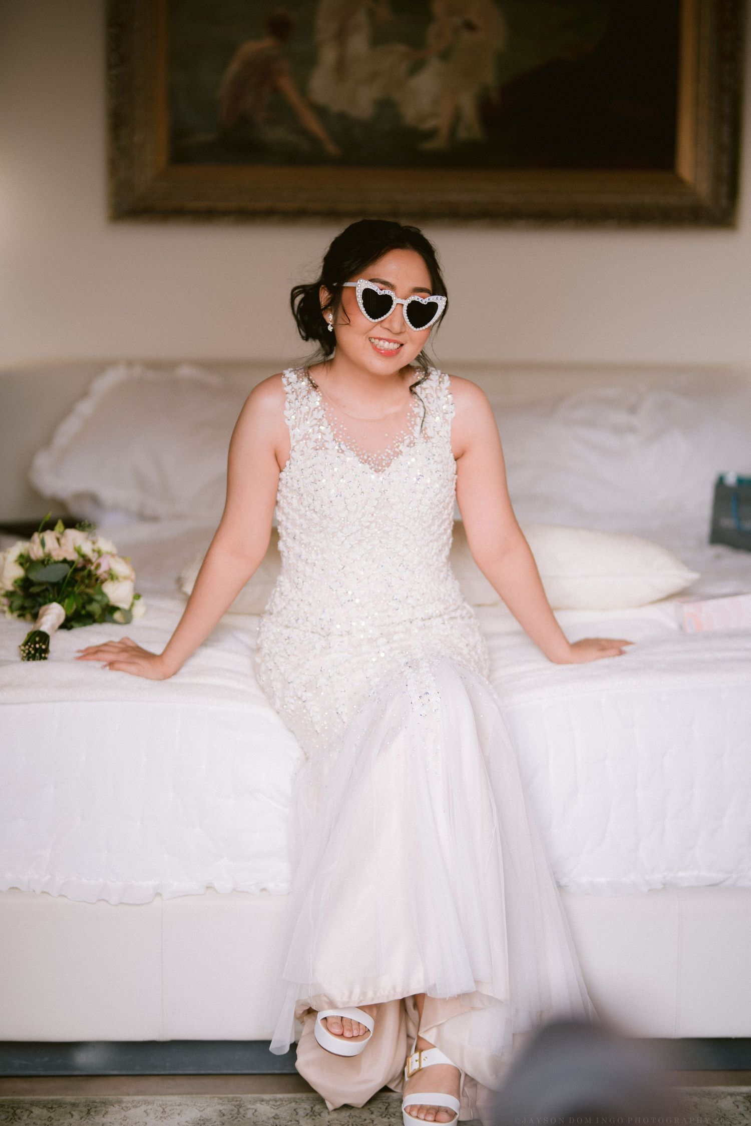 White formal dress displayed on a bed with decorative lace details and tulle skirt.