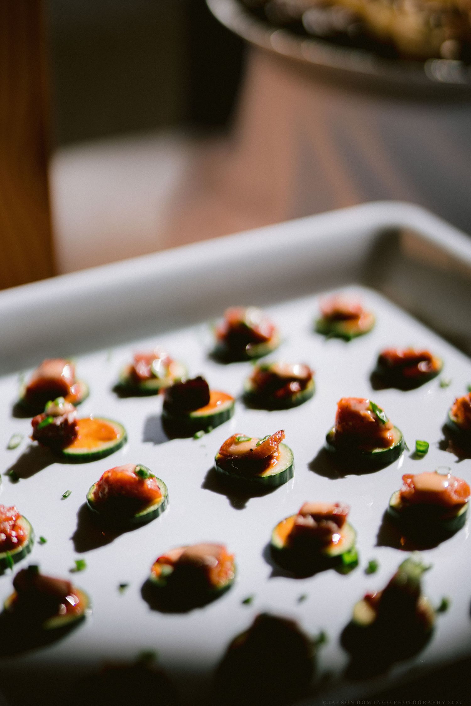 Elegant bite-sized appetizers arranged in rows on a white serving platter.