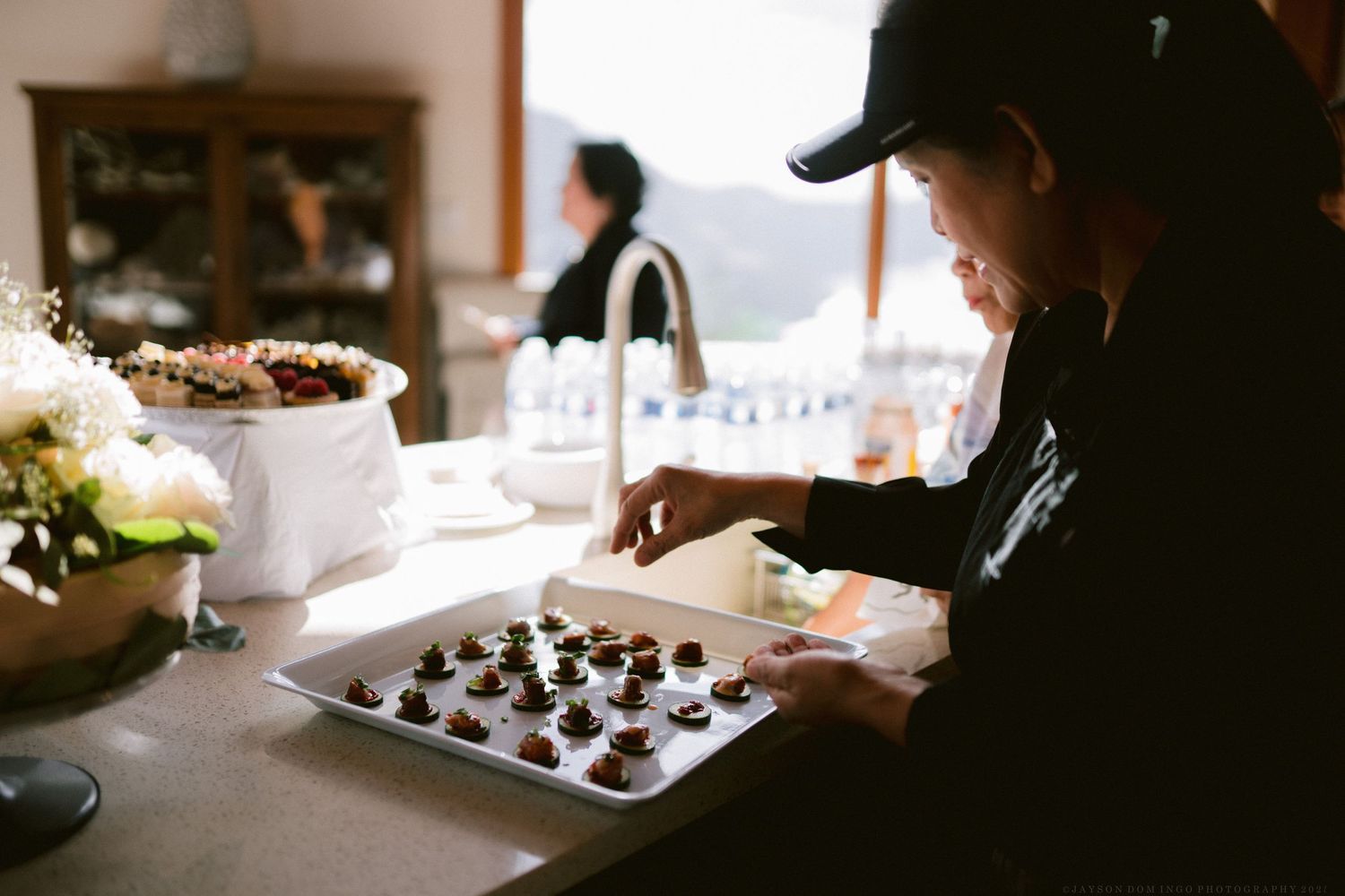 Silhouetted figures working at a table in dim lighting with natural window illumination.
