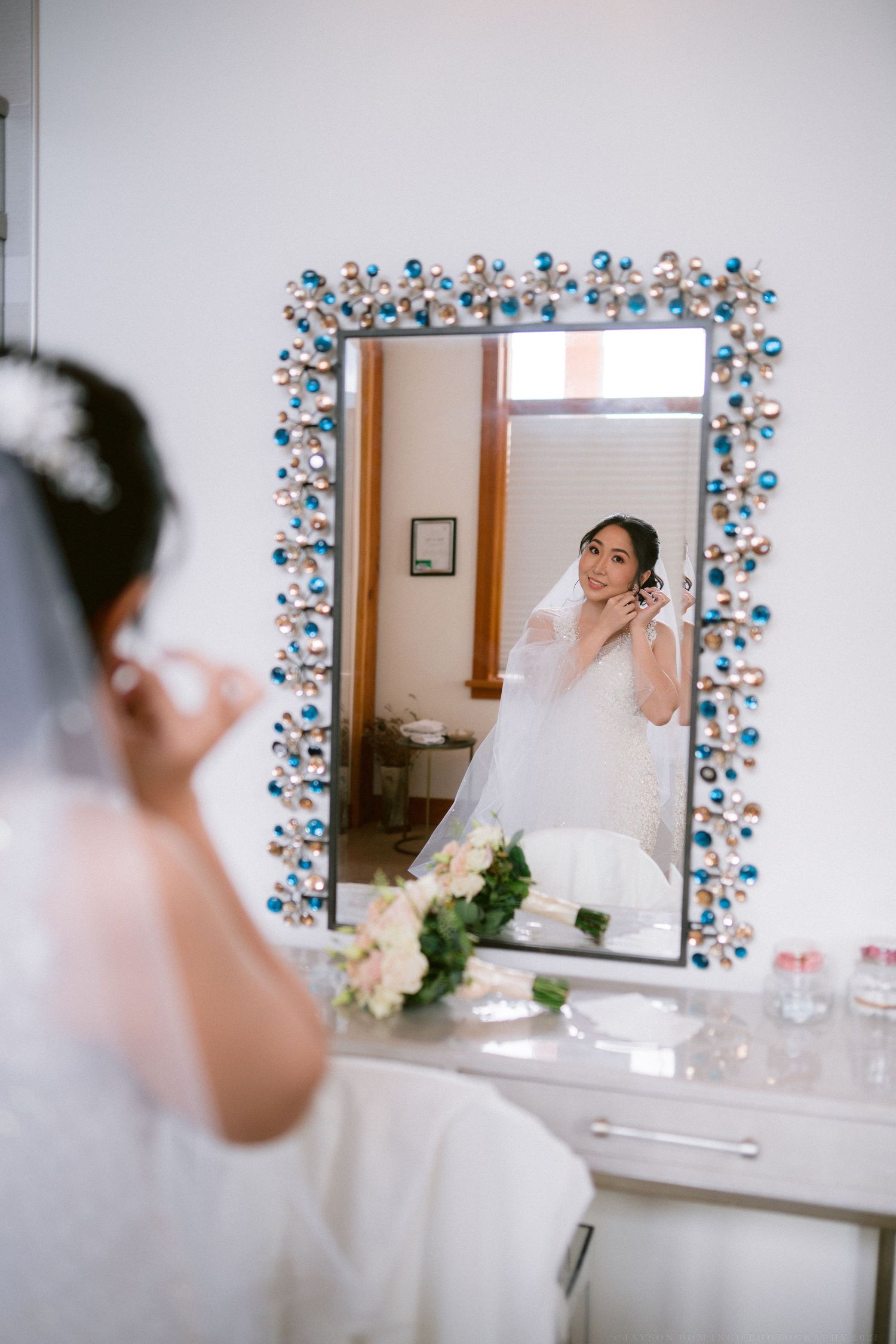 Bridal preparation room with floral-decorated mirror and vanity setup.
