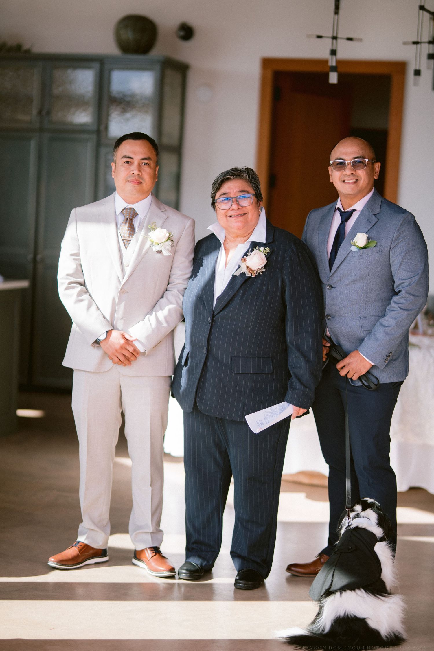 Groomsmen in light and dark suits pose together at a wedding venue.