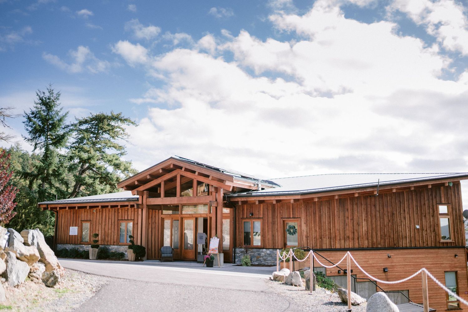 Modern wooden lodge venue with mountain backdrop and blue sky on a sunny wedding day.