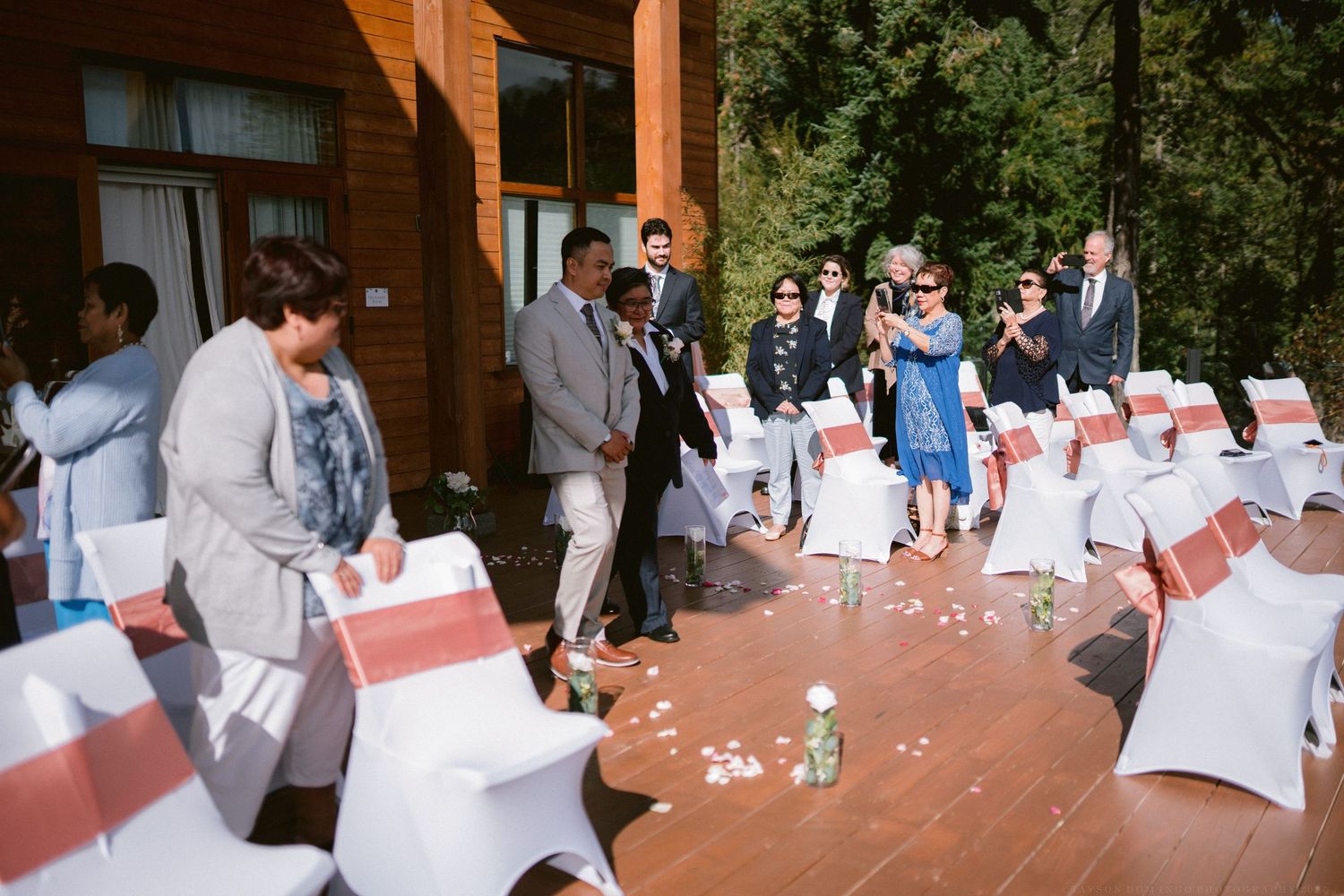 Wedding ceremony guests seated outdoors at a rustic venue with mountain views.