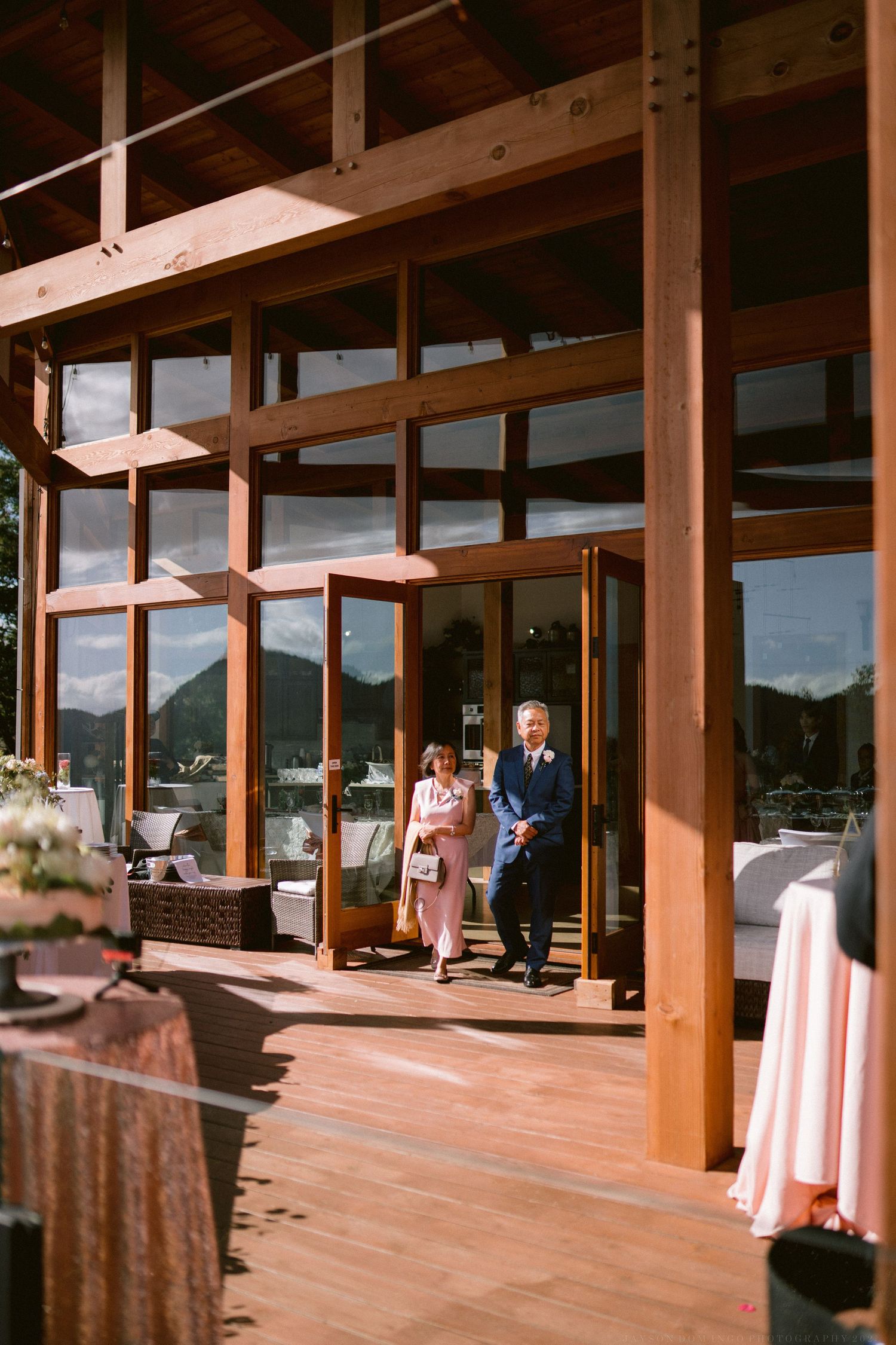 Wedding venue with wooden beams and large windows overlooking mountain scenery.