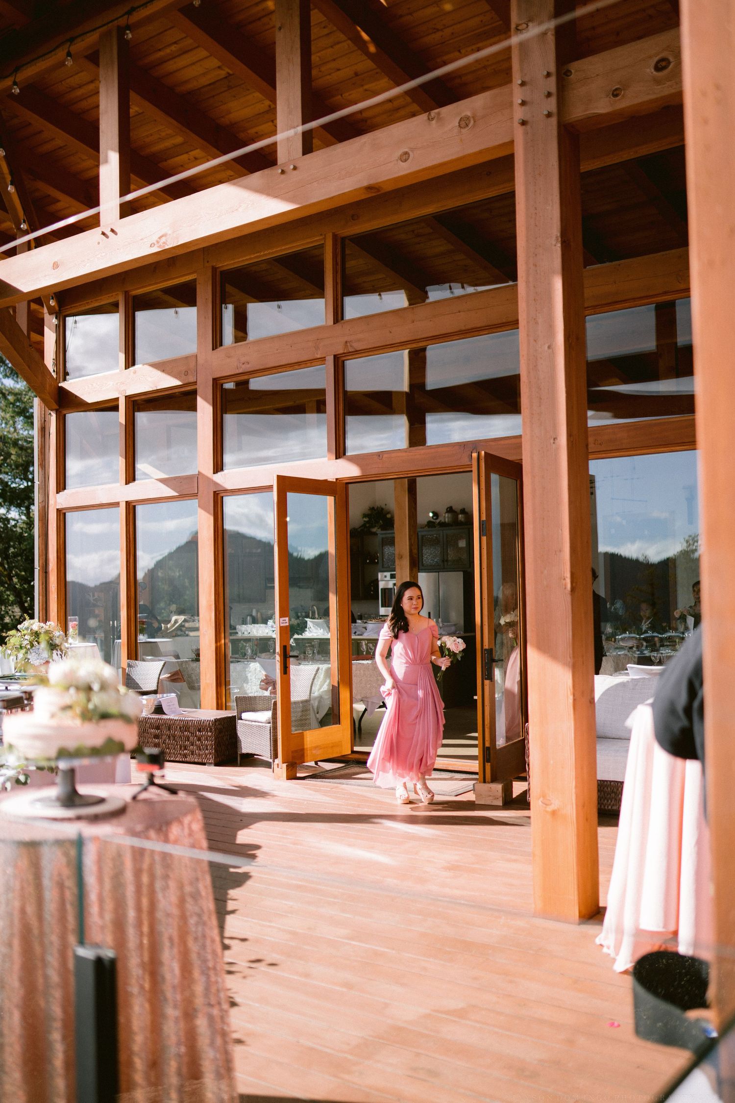 Modern wooden venue with floor-to-ceiling windows overlooking mountain views and decorated round tables.