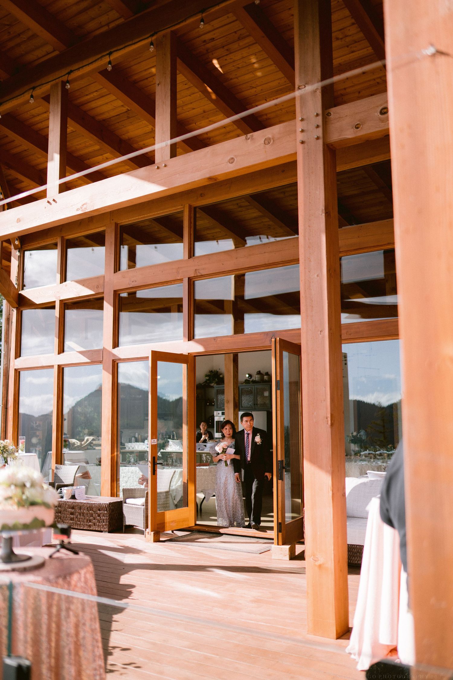 Spacious wooden deck venue with exposed beams and large windows overlooking mountain views.