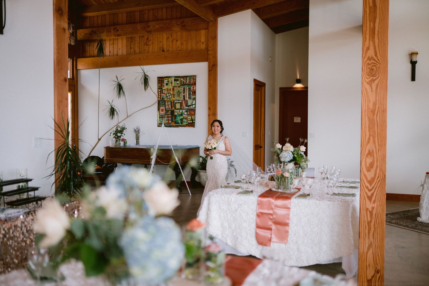 Interior of a rustic wooden event venue with exposed beams and elegant floral arrangements.