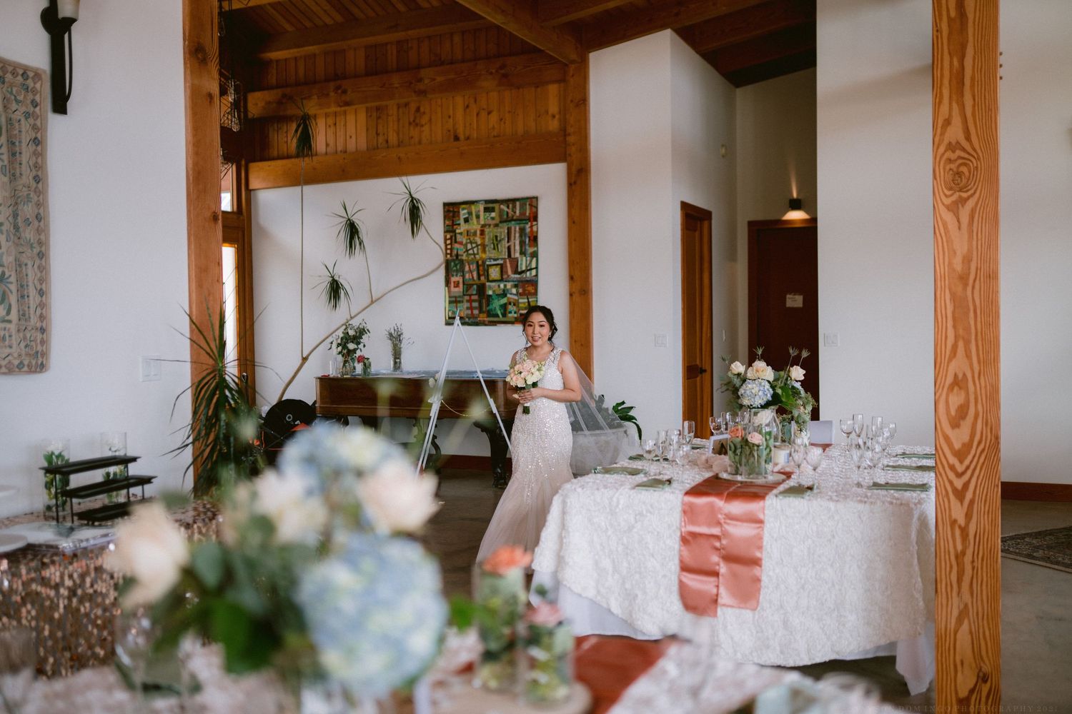 A rustic wedding reception venue with wooden beams and floral table decorations.