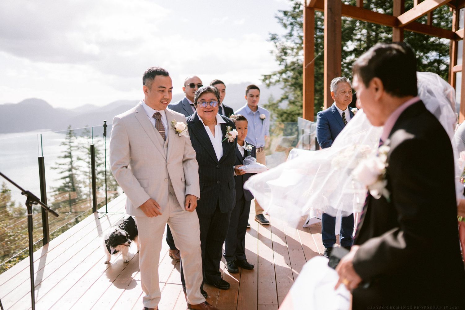 Outdoor deck wedding ceremony with mountain vista backdrop and gathered guests.