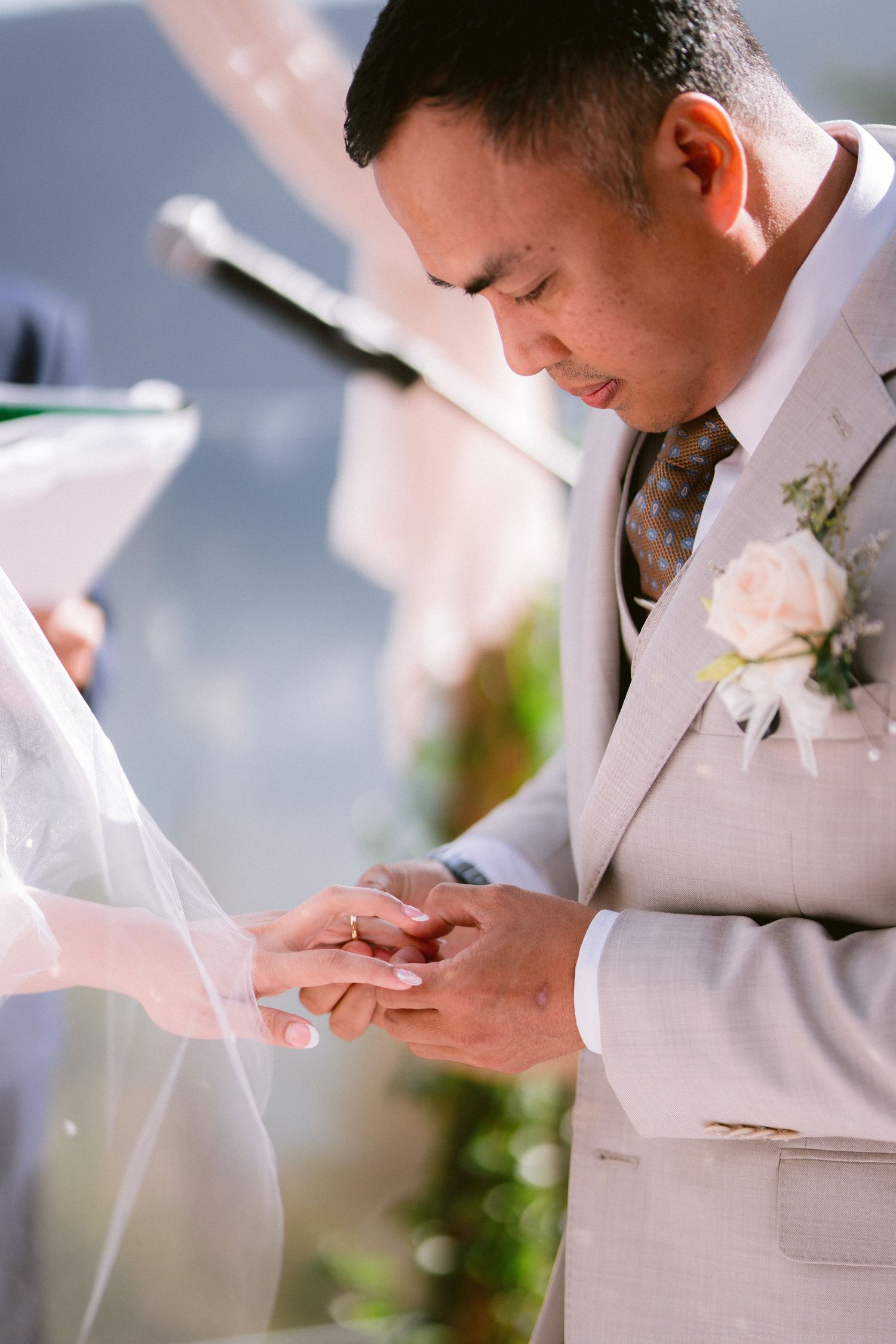 Person in light colored suit reading from paper during outdoor ceremony.