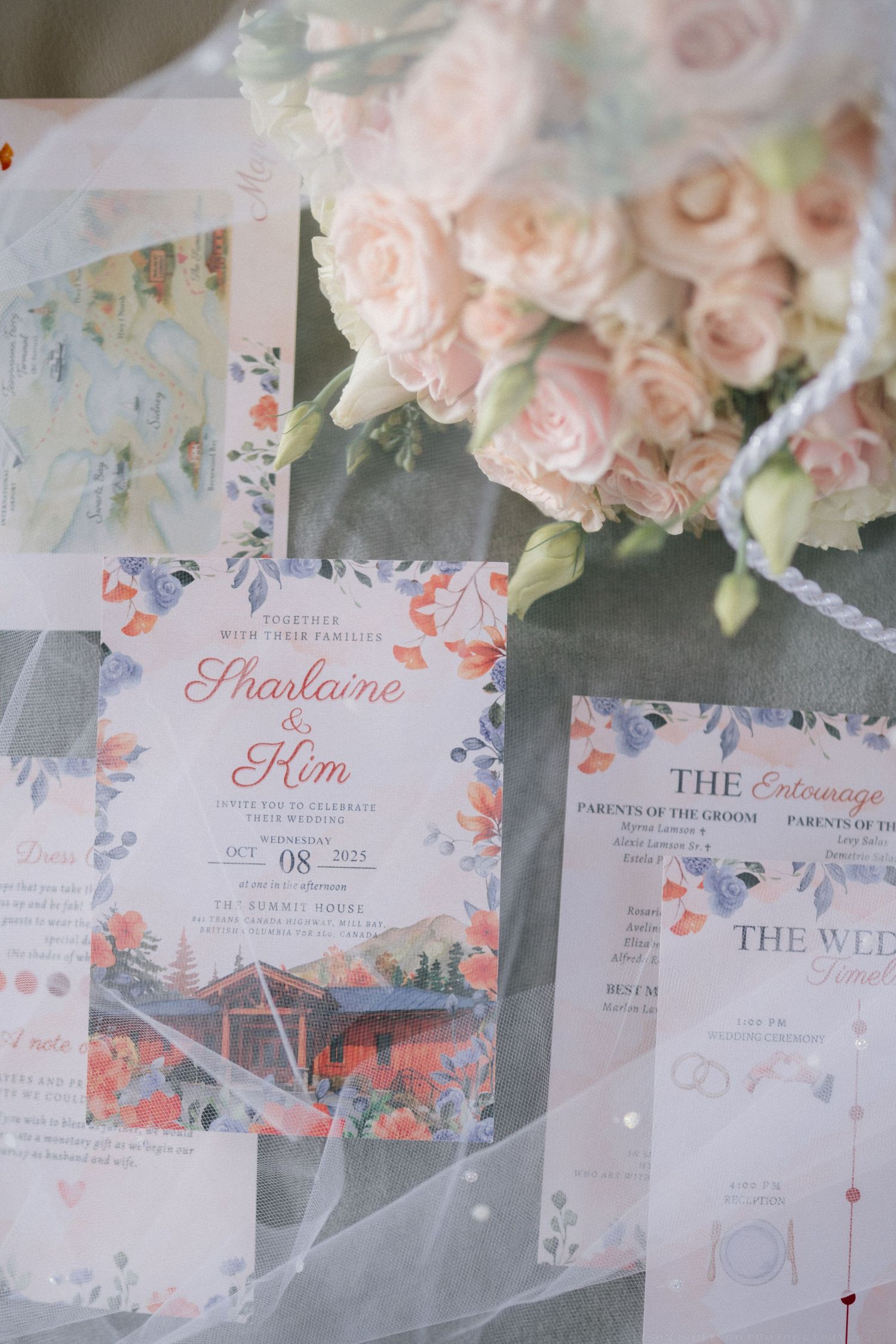 Delicate pink floral wedding invitations with watercolor designs laid out on a table.