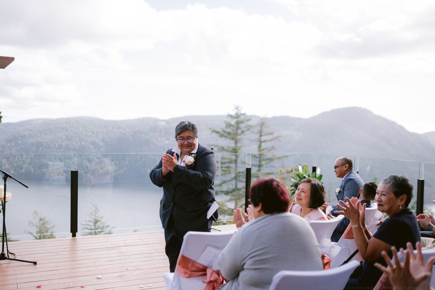 Panoramic view of wedding guests celebrating with mountains and water in the background.