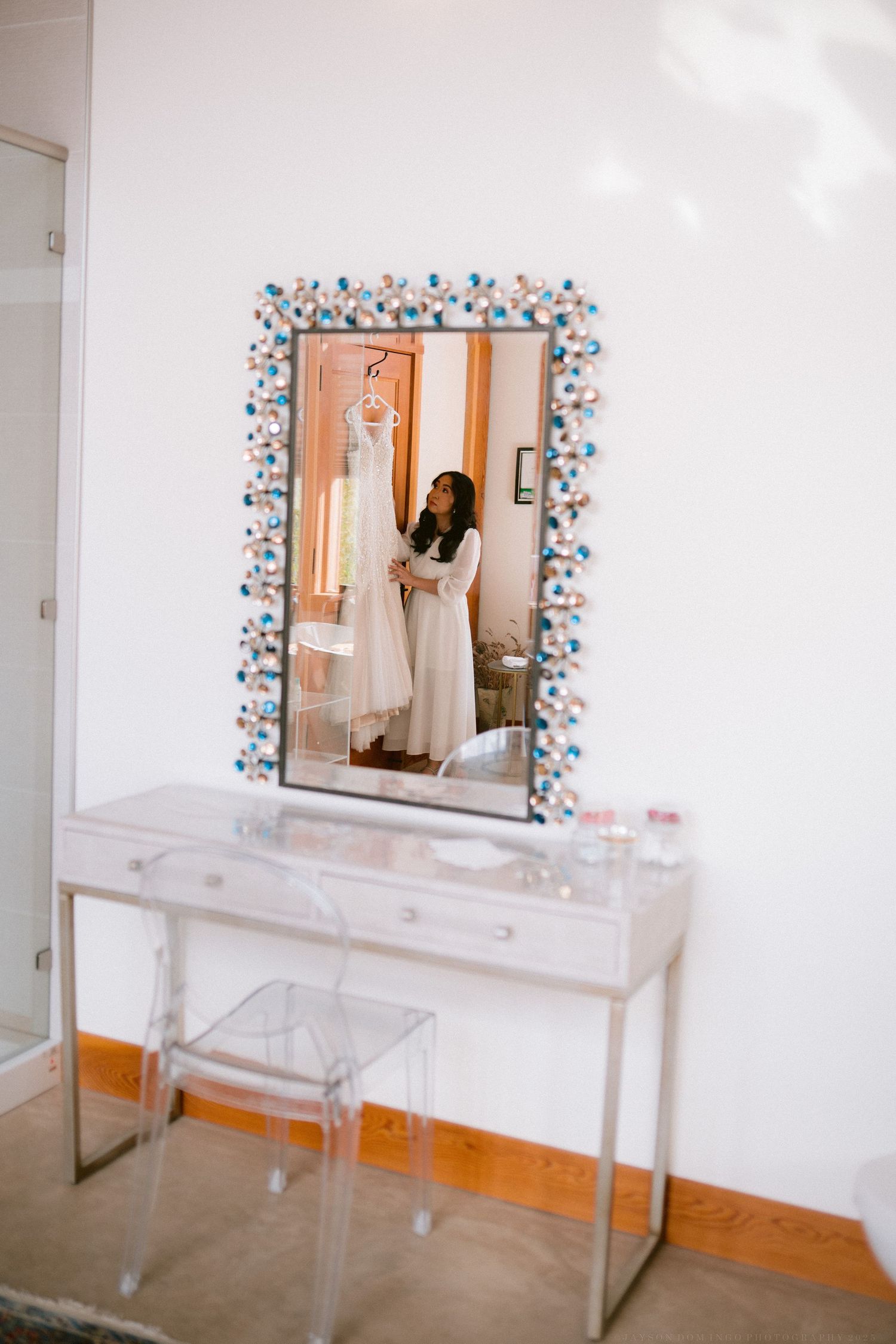 Vanity setup with decorative blue floral mirror and clear acrylic furniture.