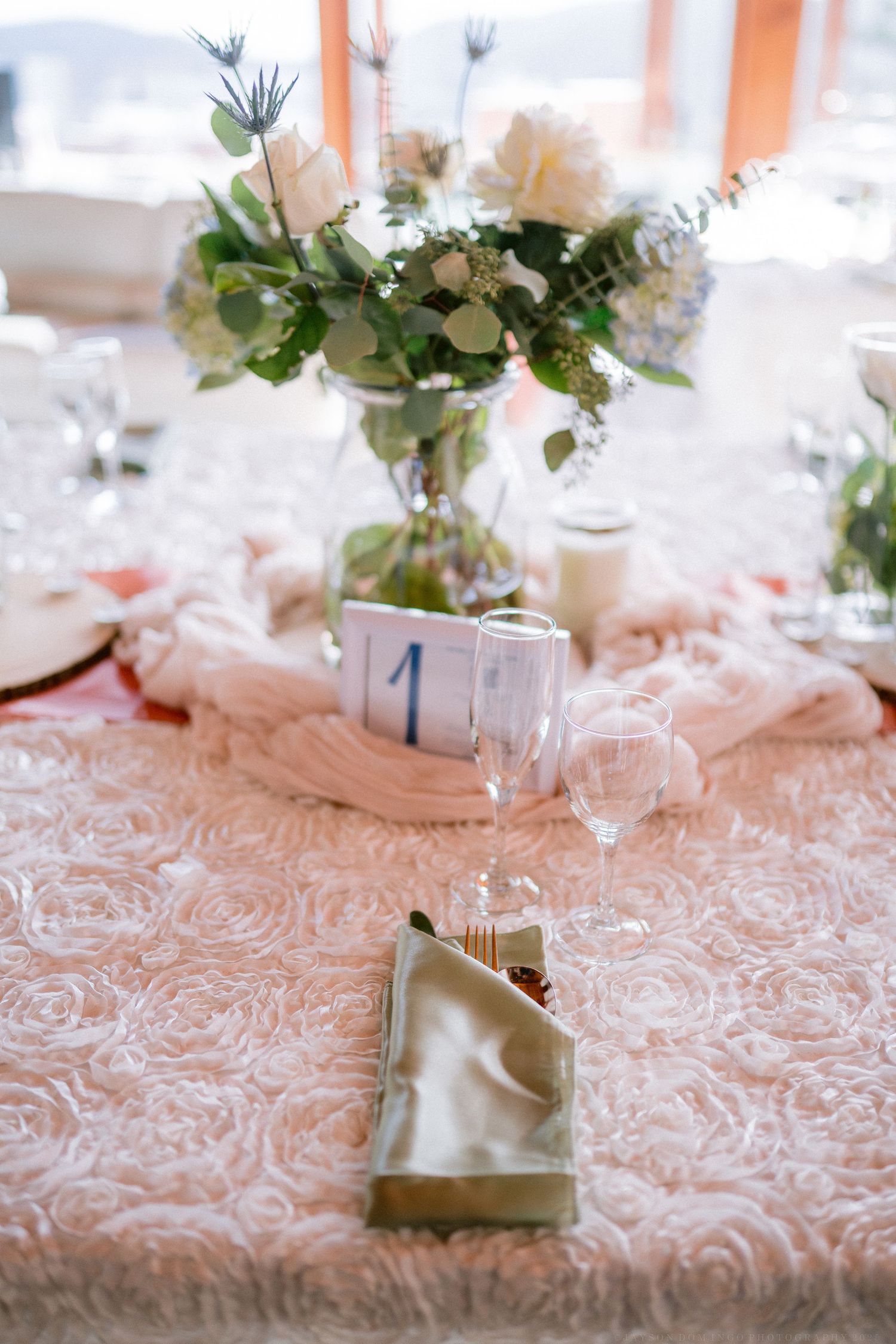 Wedding table settings with pink textured linens and delicate floral centerpieces.