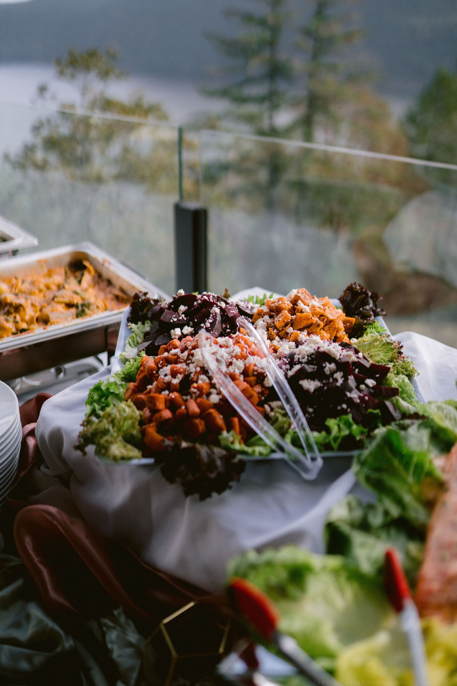Assorted fresh salads and appetizers displayed in white serving dishes at a catering event.