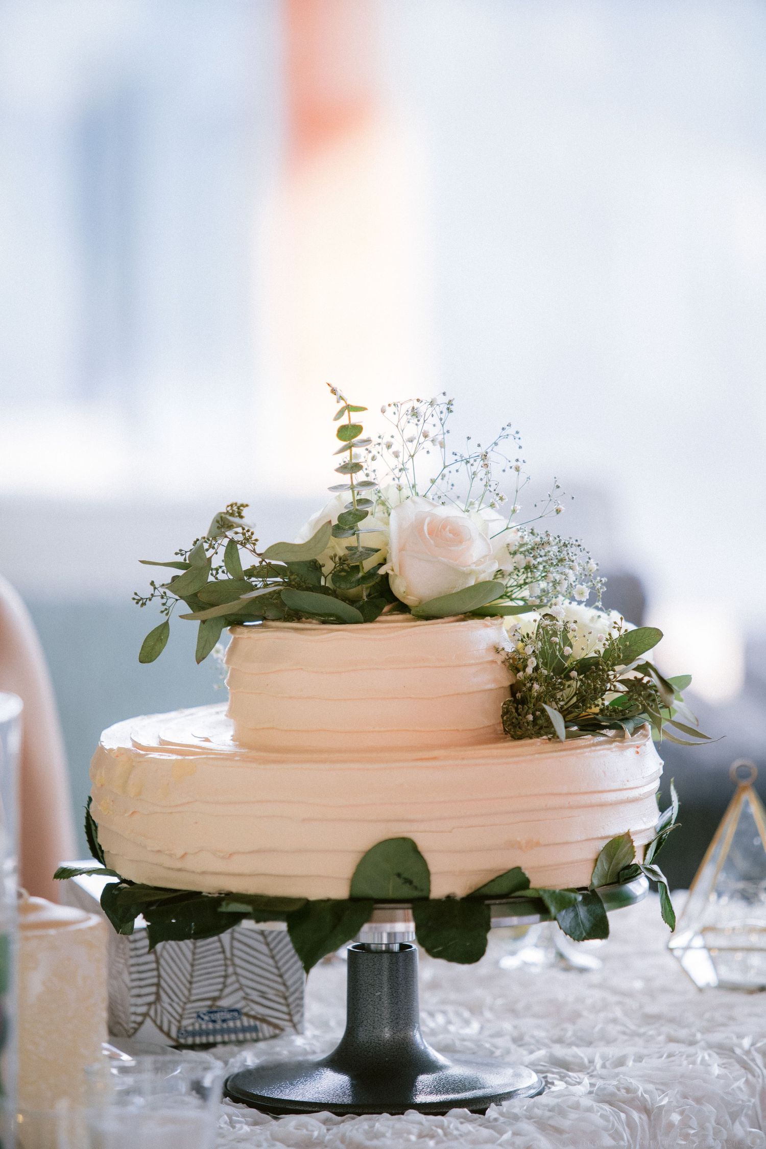 White wedding cakes decorated with fresh flowers and greenery on silver cake stands.