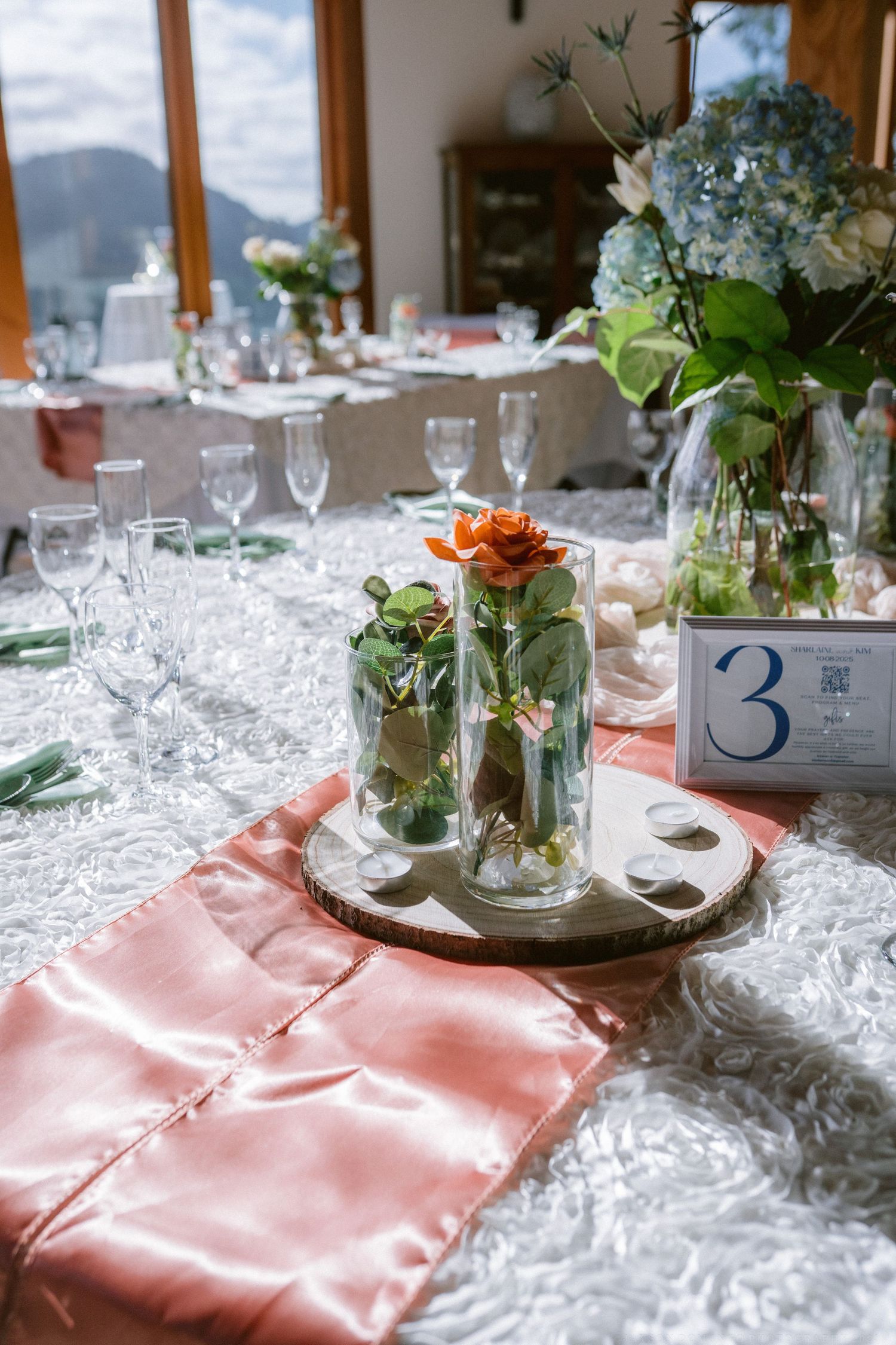 Elegant table setting with floral centerpieces and pink accents against mountain view.