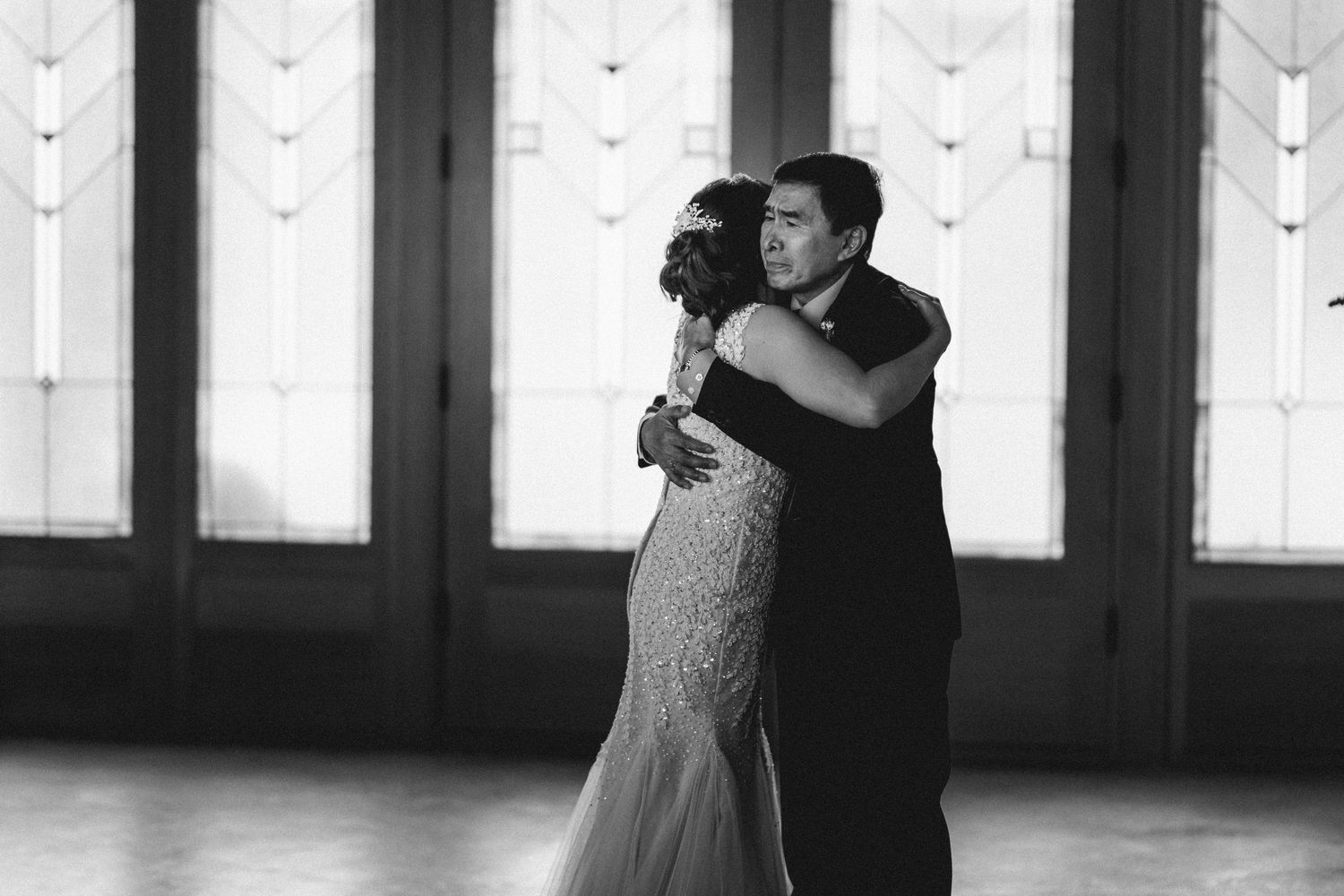 Black and white romantic dance sequence in front of large windows with dramatic lighting.