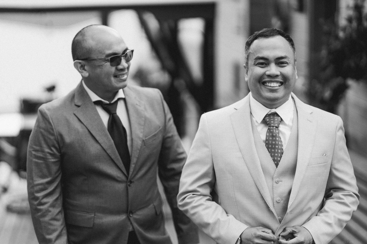 A group of people in formal business attire smile and laugh together during what appears to be a professional gathering.