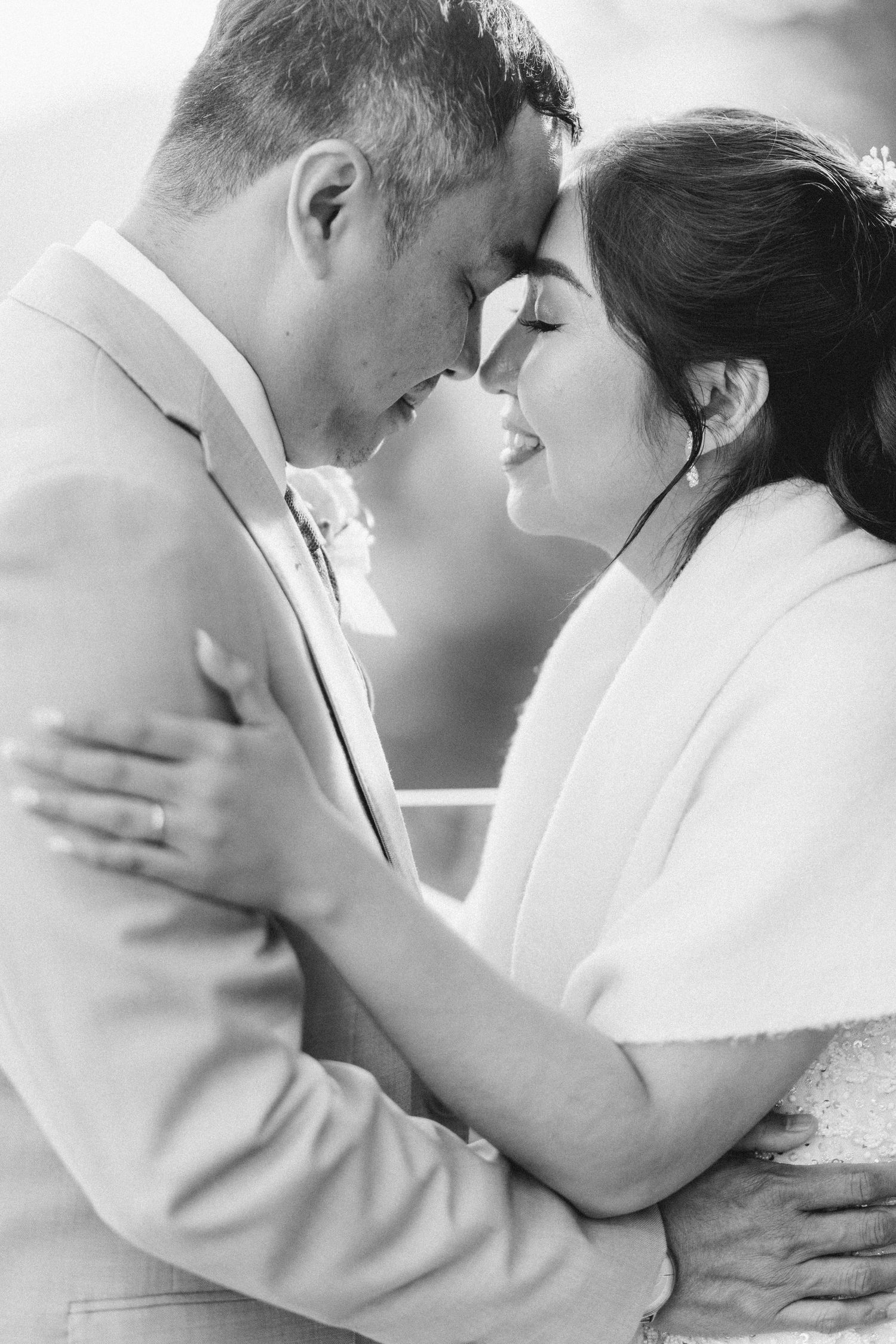 Intimate black and white portrait of newlyweds sharing tender moment.