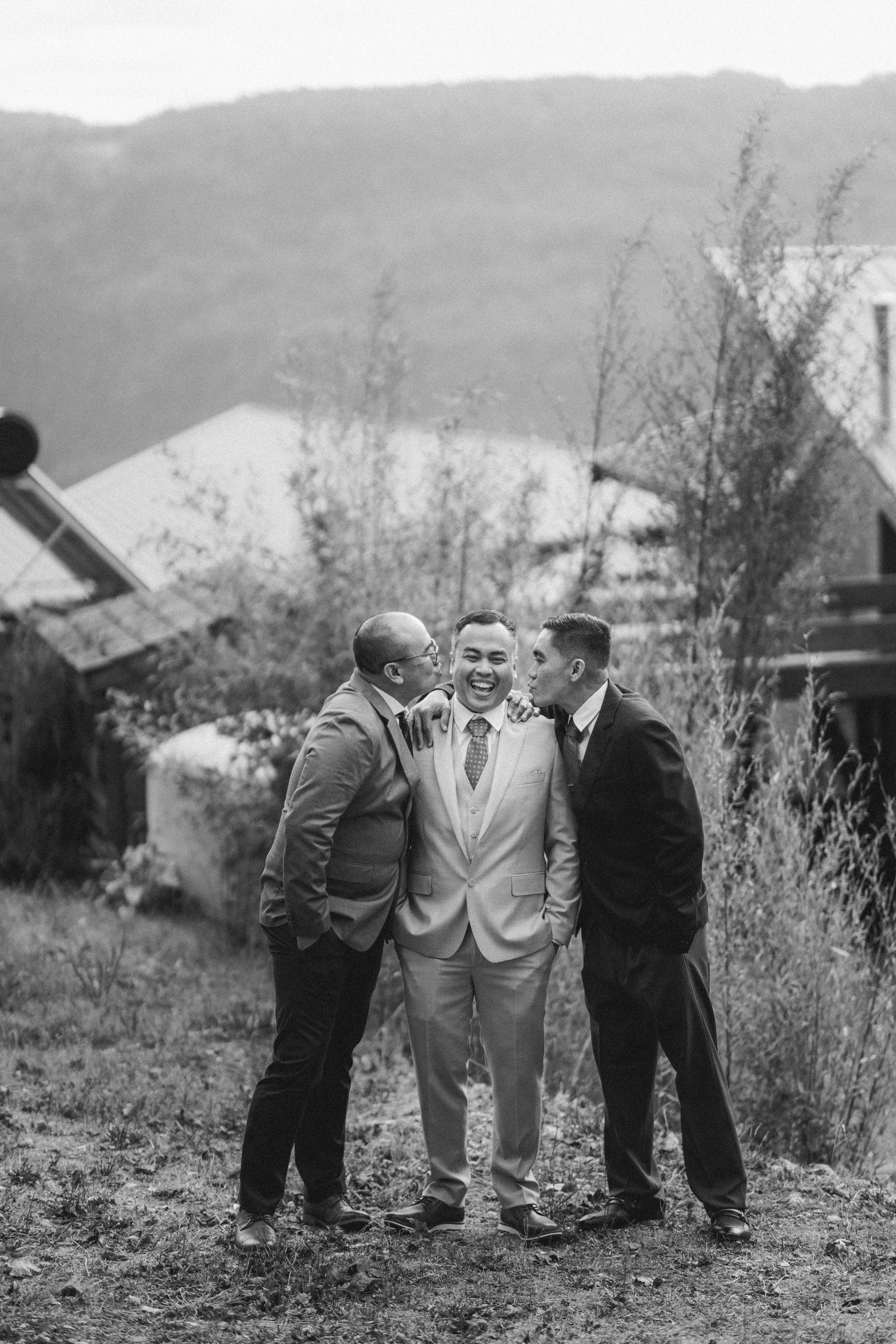Vintage black and white photograph showing three men in suits conversing outdoors on a hillside.