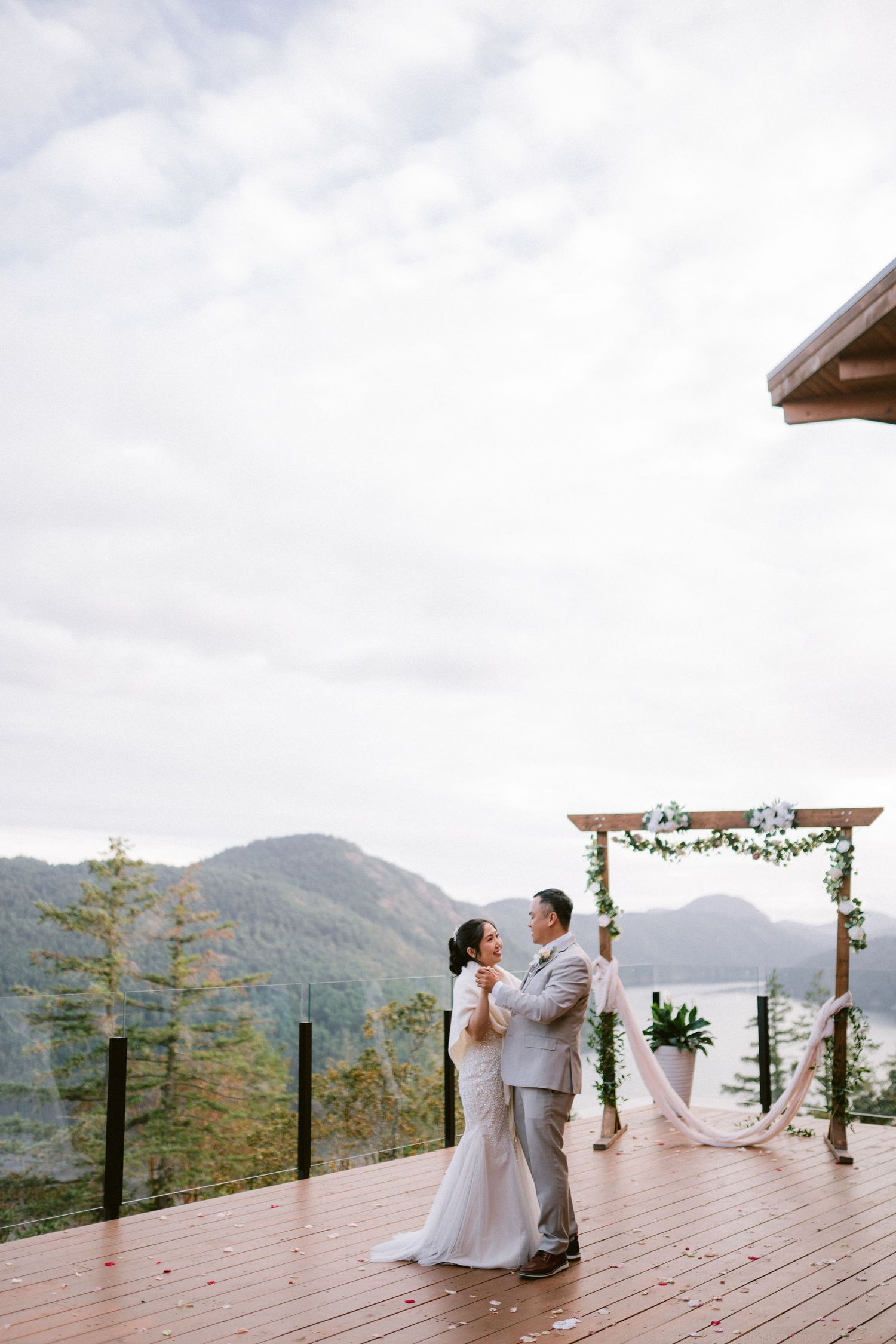A wedding ceremony setup on a deck overlooking mountain views with floral arch decorations.