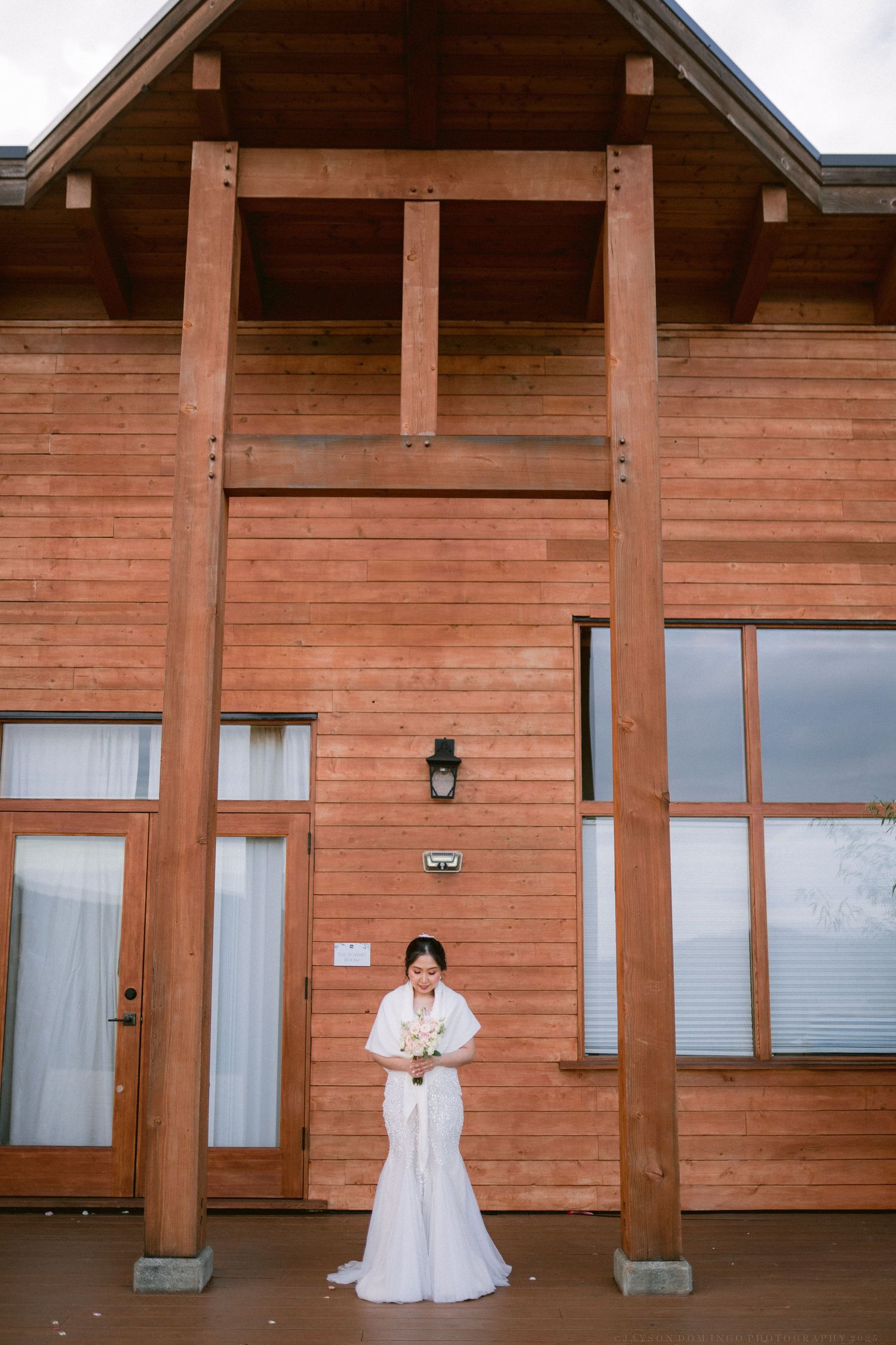 A rustic wooden lodge exterior with floor-to-ceiling windows and timber beam construction.