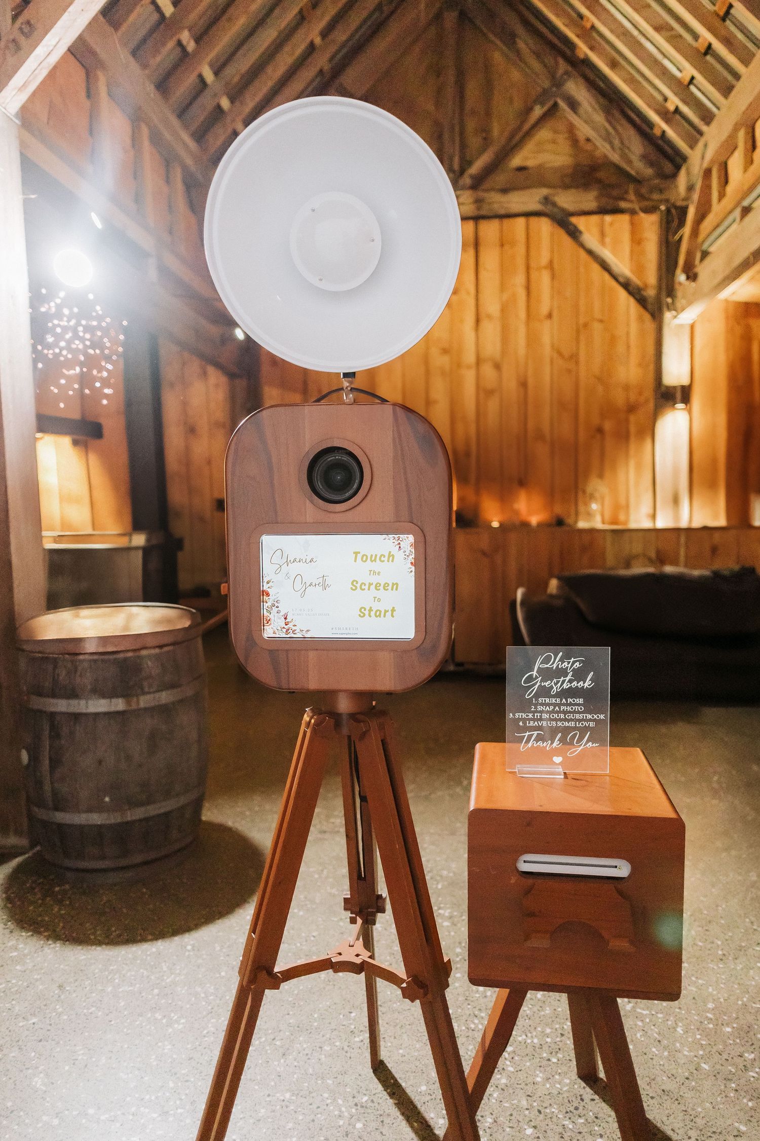Wooden wine barrel and rustic lighting display stands in a barn-style venue with warm ambient lighting.