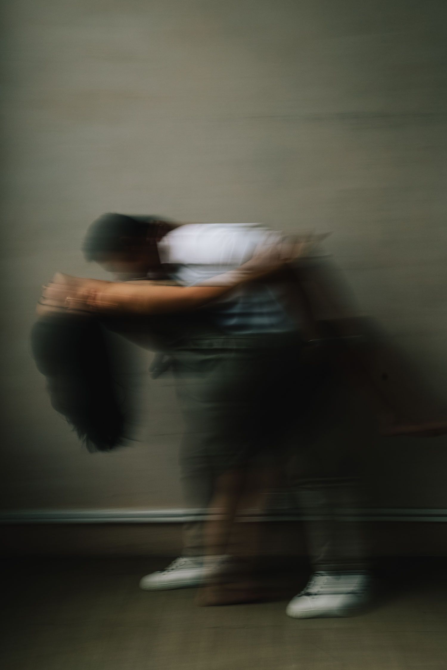 A blurred motion sequence showing a person falling or diving sideways in an abstract artistic style.