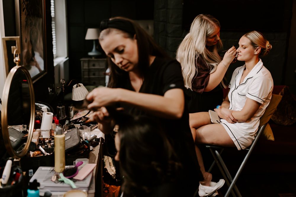 Stylist provides hair treatment services to client in modern salon setting with dark moody ambiance.