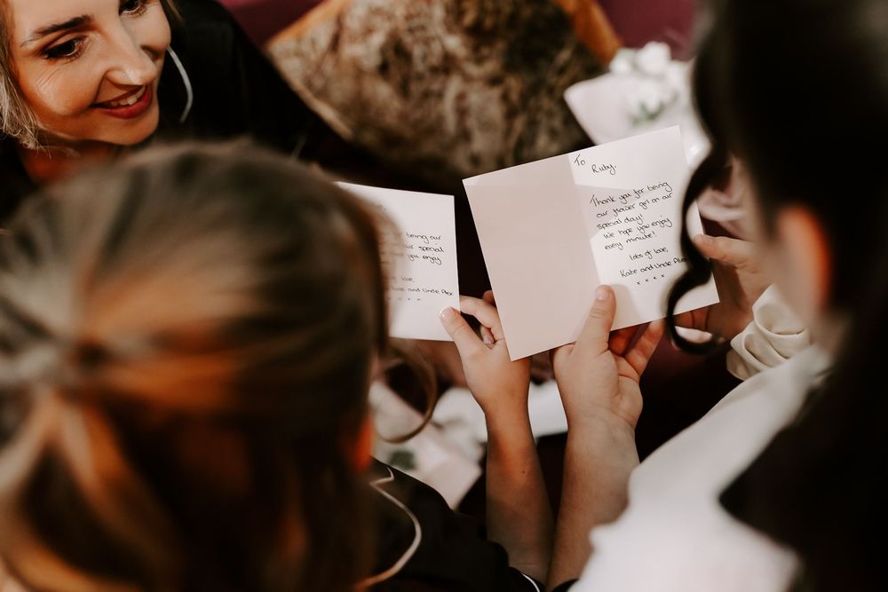 People reading handwritten notes in warm lighting during an intimate gathering.