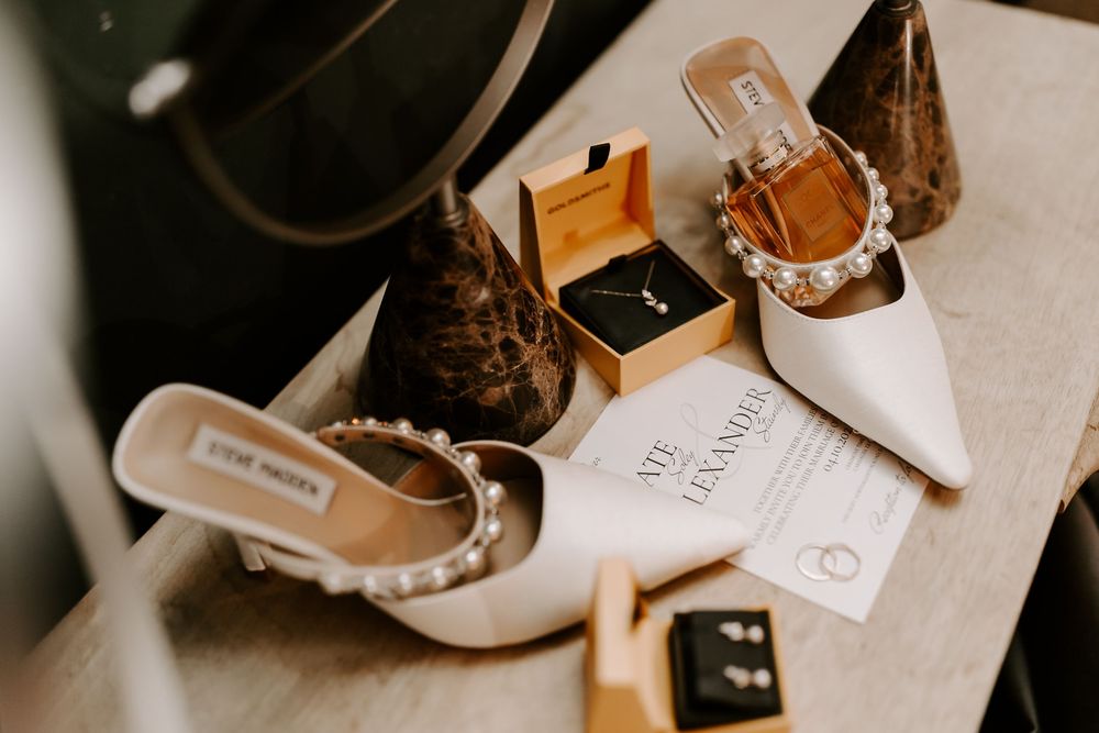 A collection of wedding preparation items including shoes, invitations, and decor arranged on a light surface.