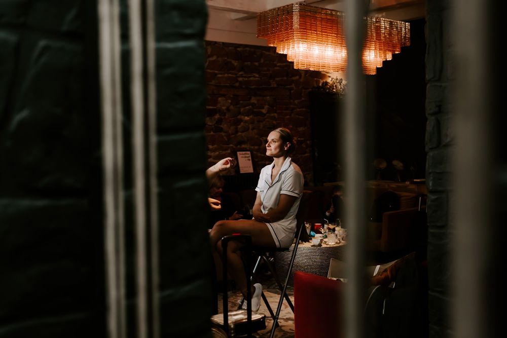Professional hairstylist working in a dimly lit salon with warm lighting and exposed brick walls.
