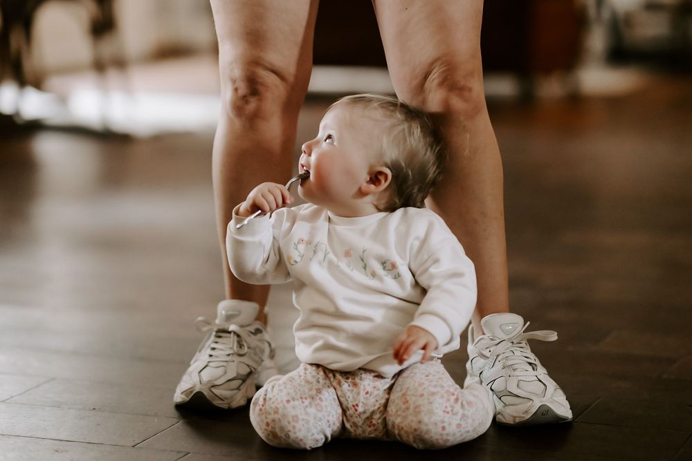 A series of five intimate sepia-toned photos showing baby feet and hands in soft lighting.