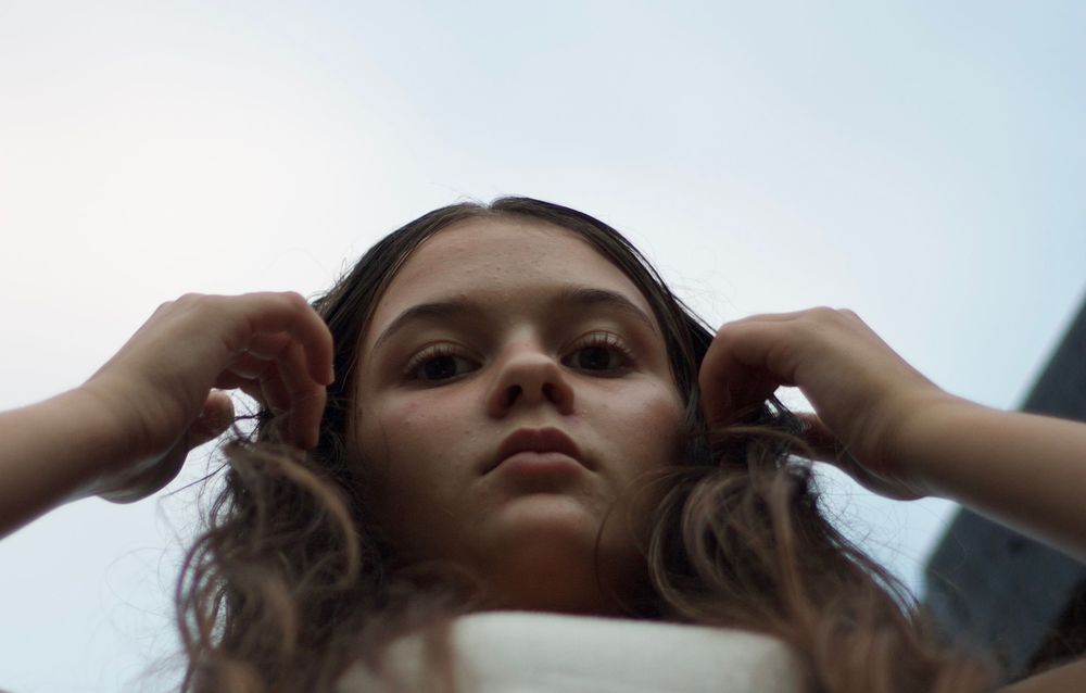 Artistic portrait series showing dramatic angles and poses against a bright sky background.