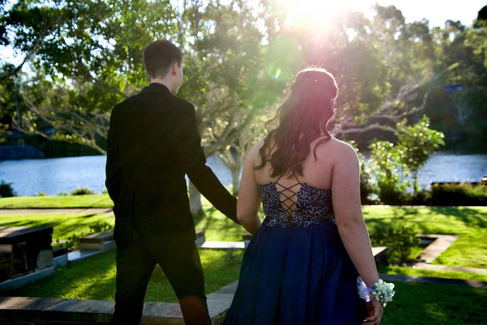 A couple poses for romantic photos in a sunlit garden setting.