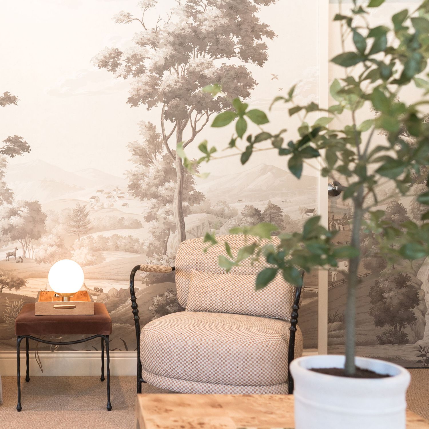 Modern minimalist waiting room with wall mural, potted plants, and contemporary furniture.