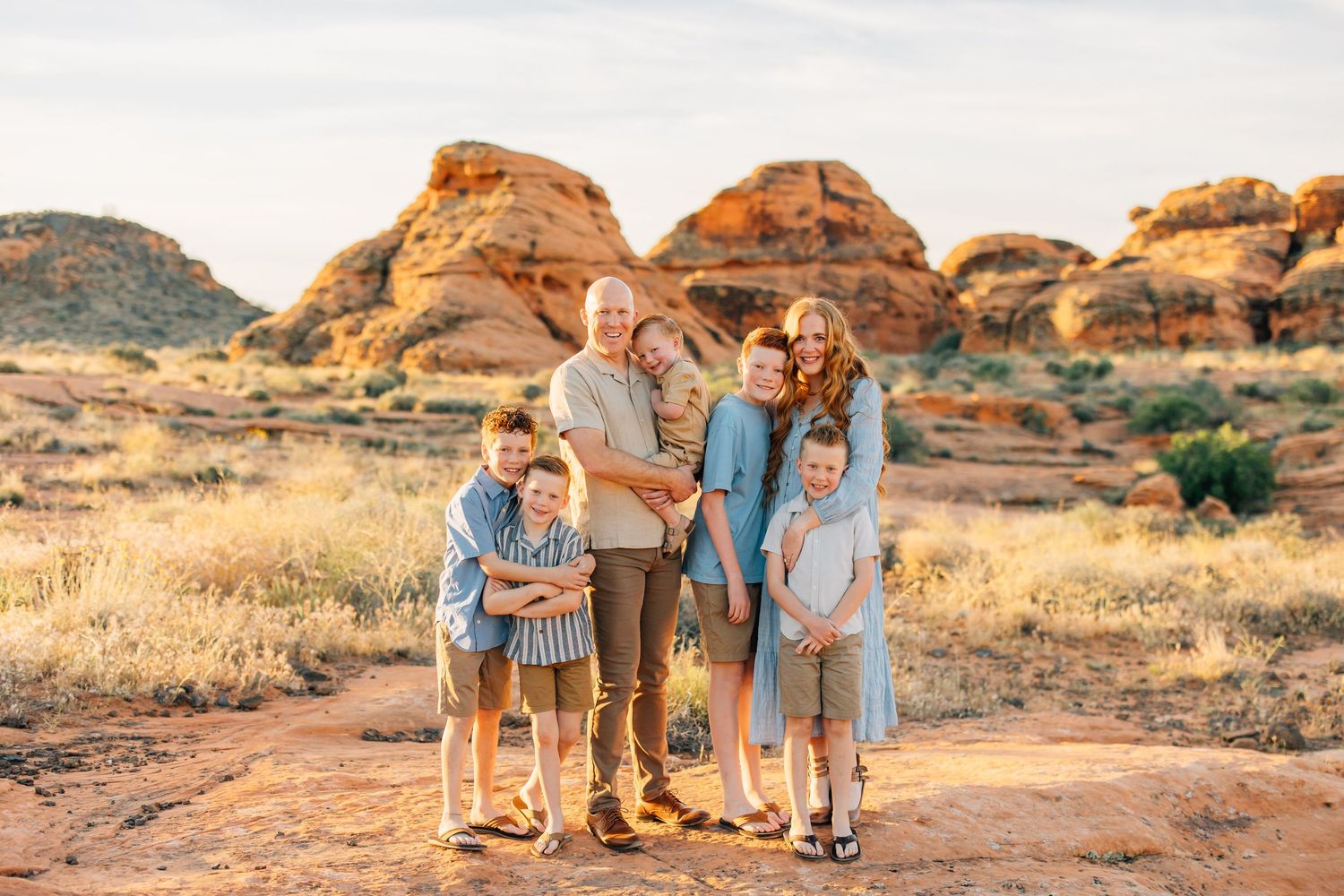 Family portrait session in golden autumn field with mountains in background.