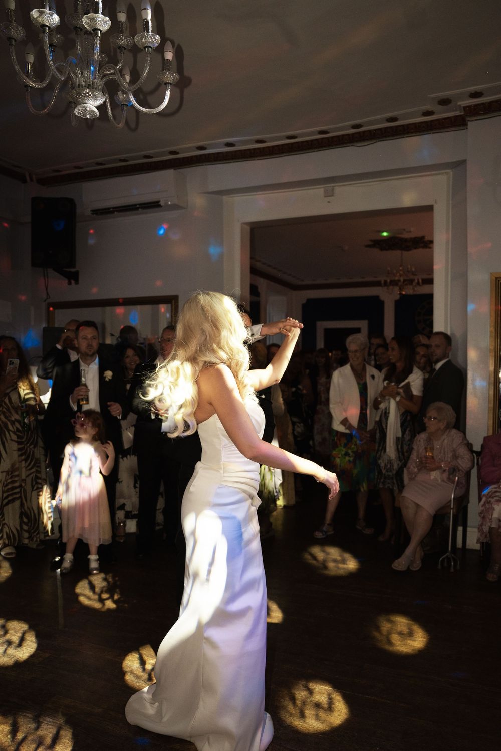 A sequence of dance photos showing someone in a white dress twirling and moving across a dimly lit dance floor at an event.