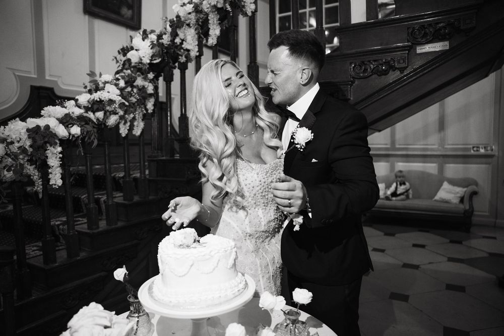 A bride and groom share a romantic moment during their wedding reception while cutting their elegant white cake.