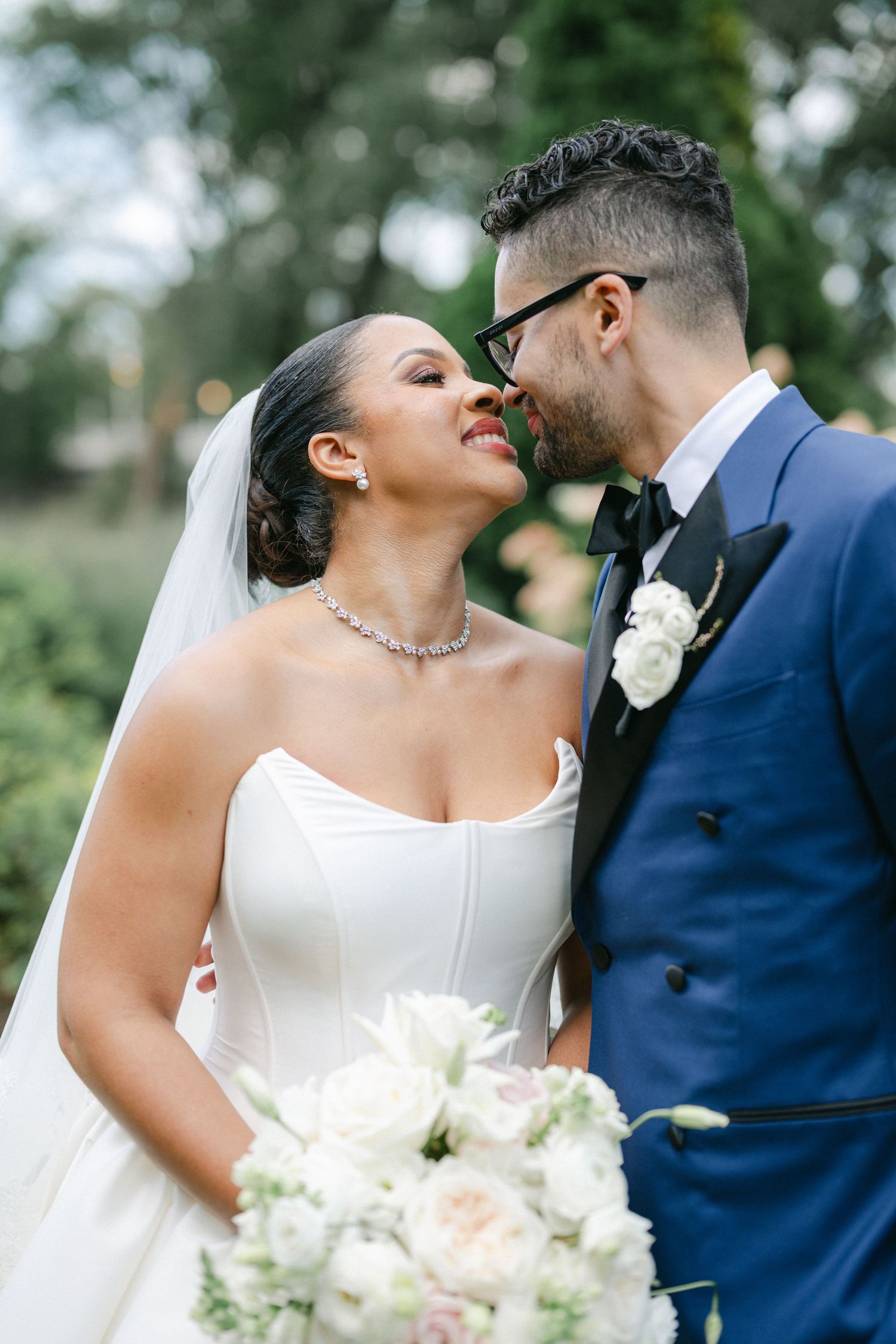 A joyful couple shares intimate moments in their wedding attire, with the bride holding a beautiful white and blush bouquet.