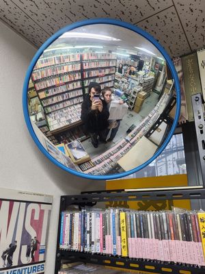 Curved security mirrors mounted on walls show reflections of library bookshelves and aisles in multiple views.