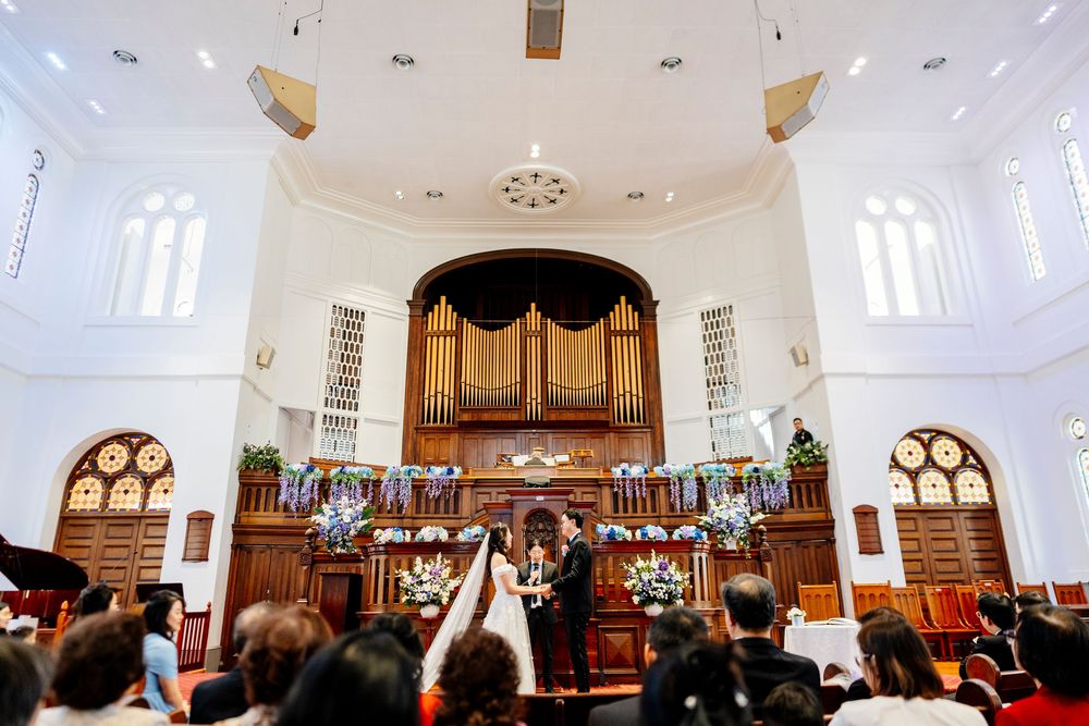 Wedding ceremony in a grand church with high ceilings, wooden beams, and an organ at the altar.