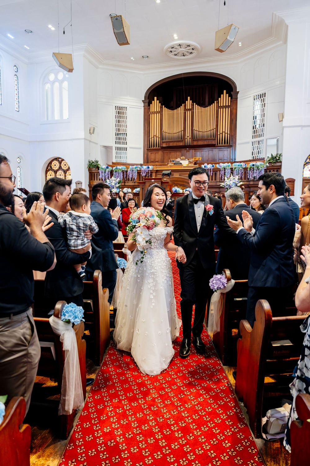 Wedding celebration inside a church sanctuary with red carpeting and a pipe organ in the background.